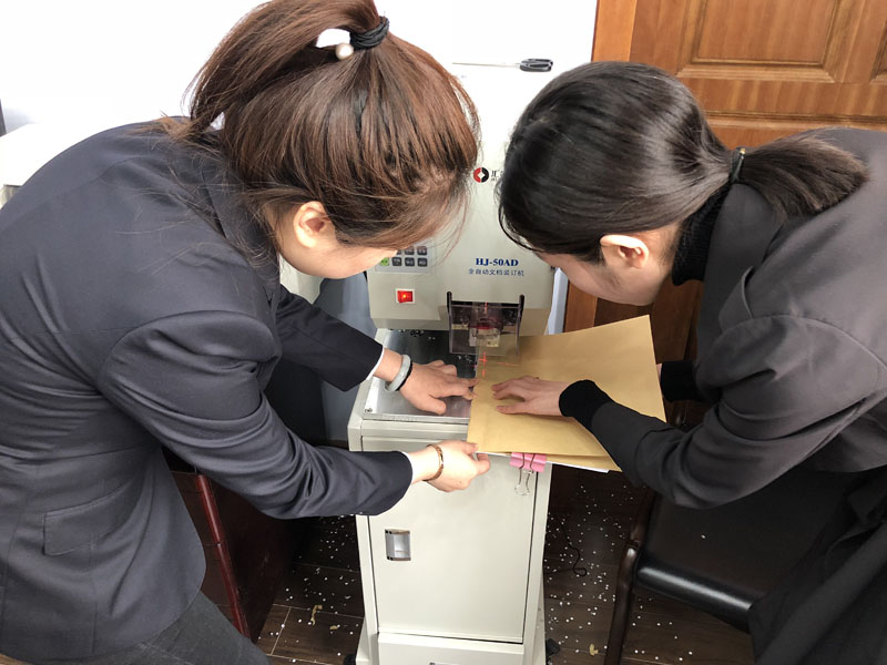 圖二：記者（左一）在工作人員的幫助下裝訂了一本案卷。