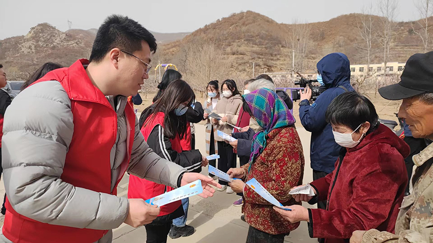 李田野(左一)向村民發(fā)放普法宣傳材料
