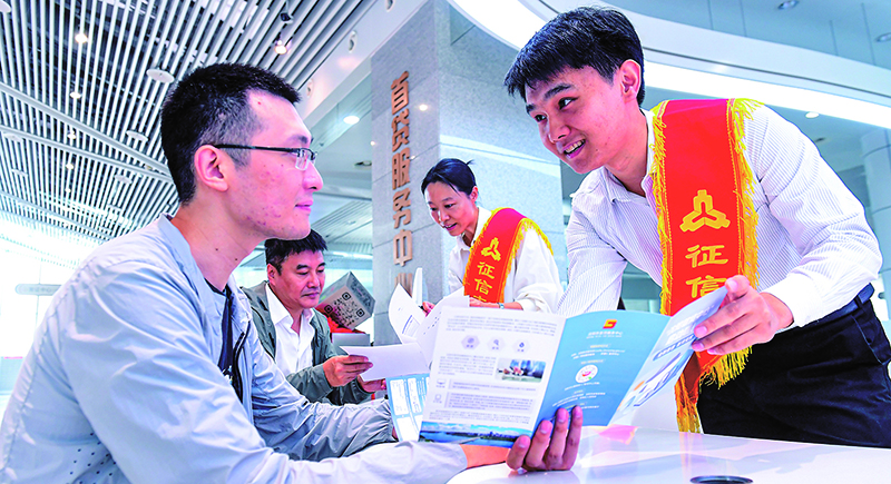 征信志愿服務(wù)大隊(duì)志愿者在首貸服務(wù)中心為前來咨詢征信業(yè)務(wù)的群眾進(jìn)行業(yè)務(wù)講解