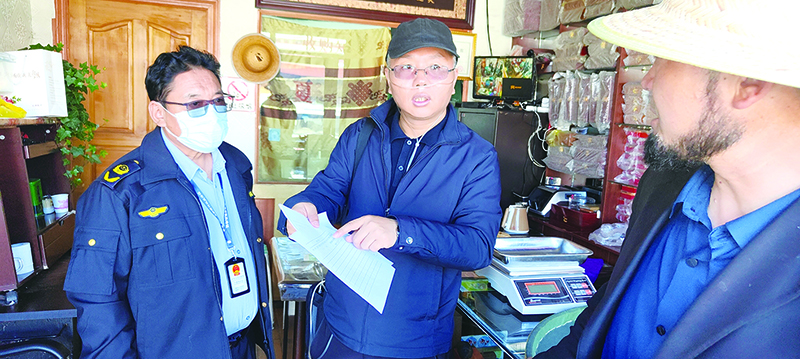麻小軍（右一）與那曲市場監(jiān)管局執(zhí)法人員指導商戶如何建立銷售臺賬。