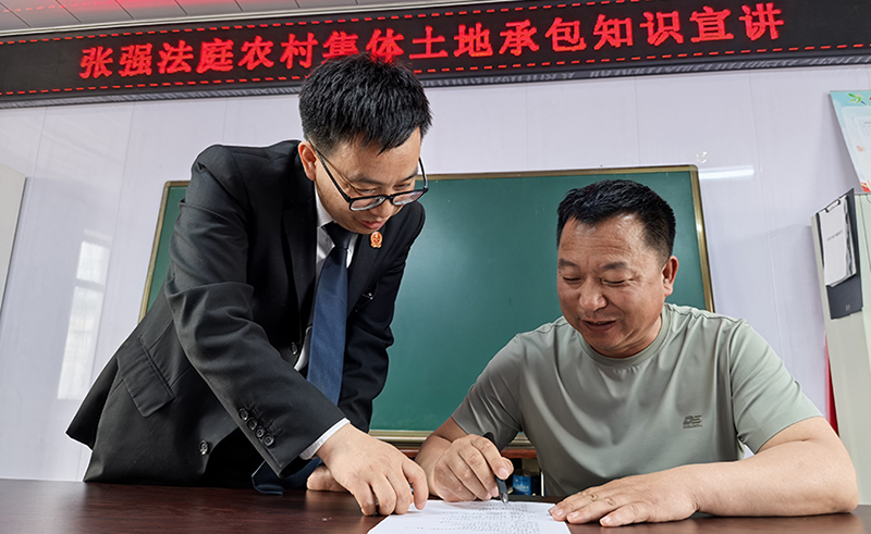 張強人民法庭庭長田芝濤(左)指導(dǎo)村民如何填寫“普法清單”